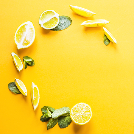Pieces of lemon, lime and green mint leaves lined in a circle on a yellow background. Summer products for making lemonade. Top view, flat lay, copyspaceの写真素材