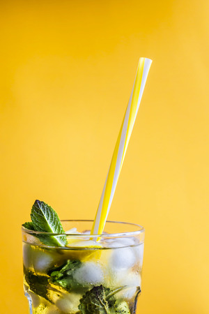 Ice tea with ice, lemon and mint on a combined colored yellow background. Summer cold drink cocktailの写真素材