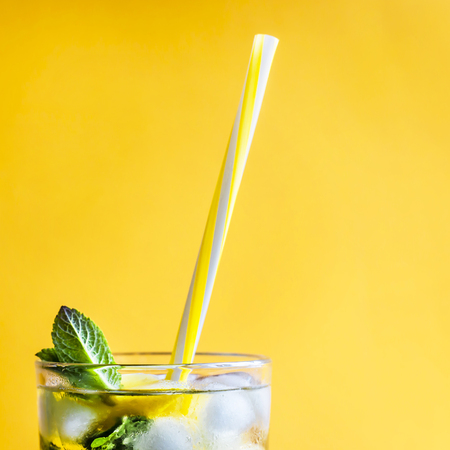 Ice tea with ice, lemon and mint on a combined colored yellow background. Summer cold drink cocktailの写真素材