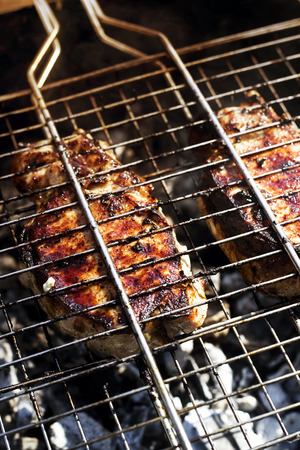 Two pork steaks on the grid are prepared on the grill outdoor. Summer family barbecue conceptの写真素材
