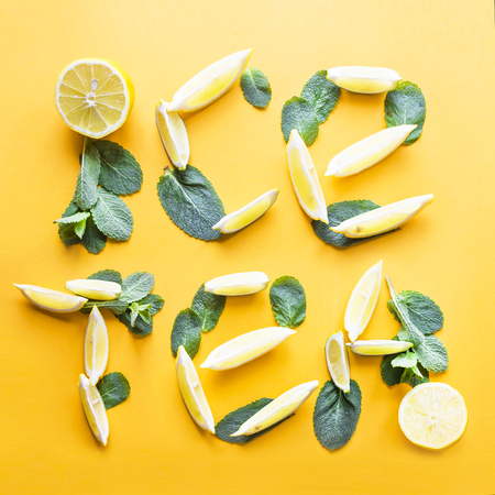 Words cold tea are lined on a bright yellow background from the lobes of lemon and mint. Cold summer drink conceptの写真素材