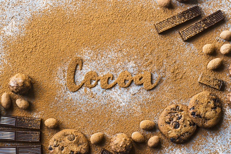 The word cocoa is written on the background of cocoa powder next to chocolate biscuits and candy. I love chocolate conceptの写真素材