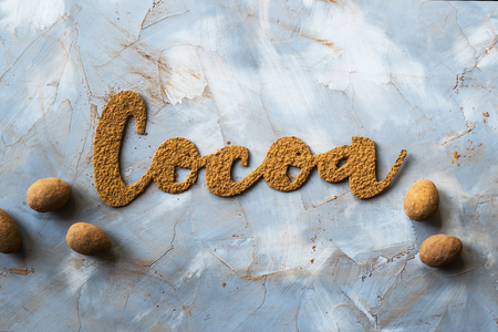 Sloka cocoa is written in letters of cocoa on a gray background next to candy nuts in chocolate. I love chocolate conceptの写真素材