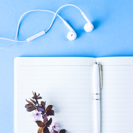 Open notebook with headphones on a blue background. Spring workplace conceptの写真素材