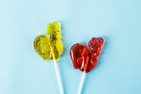 Red and yellow candy in the shape of a cockerel - retro sweets. On blue background. Top view, flat layの写真素材
