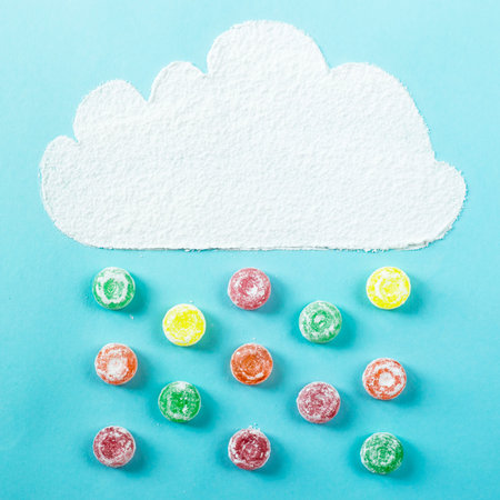 A cloud of powdered sugar from which comes the candy rain lined on a blue background. Unhealthy...