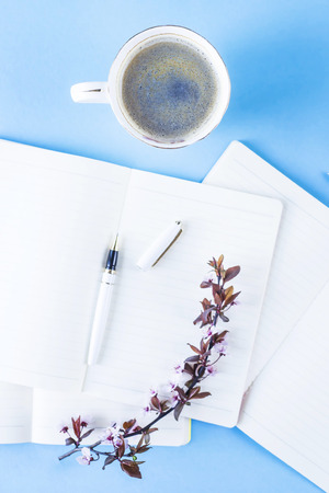 A stack of three notebooks on a creative workplace with flowering branches on a blue background.
Spring workplace concept.の写真素材