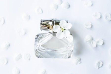 A glass jar of perfume among white spring petals. Women's fragranceの写真素材
