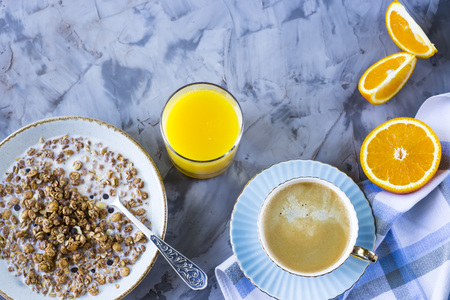 A healthy breakfast of chocolate muesli with coffee, oranges and juice on a gray background. Top view, flat lay, still lifeの写真素材