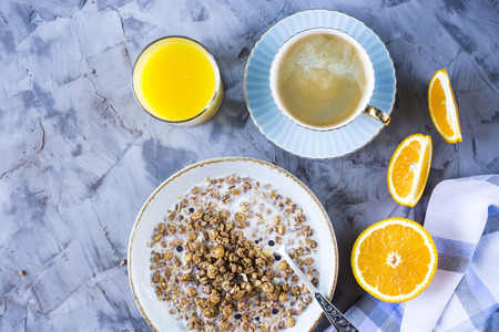 A healthy breakfast of chocolate muesli with coffee, oranges and juice on a gray background. Top view, flat lay, still lifeの写真素材