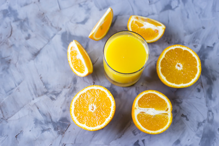 Sliced orange next to a glass of orange juice on a gray backgroundの写真素材