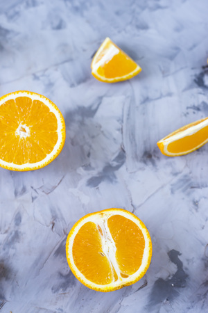 Sliced orange with various pieces on a gray background. Top view, flat layの写真素材