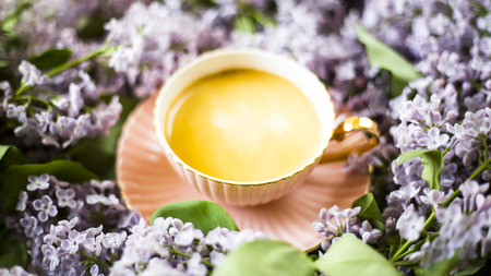 A pink cup of coffee with lilac flowers on a gray concrete table. Spring conceptの写真素材