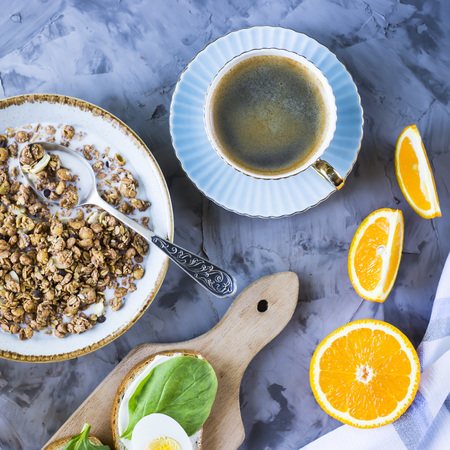Healthy hearty breakfast - muesli, sandwich with egg, coffee, orange and juice on a gray background. Top viewの写真素材