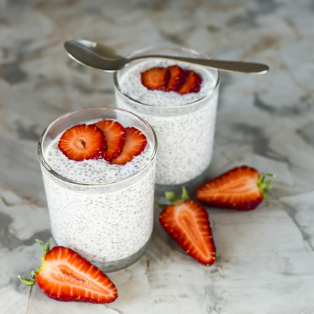 Two servings of dessert made of chia seeds, milk and strawberries on a gray table. Healthy Breakfast Conceptの写真素材