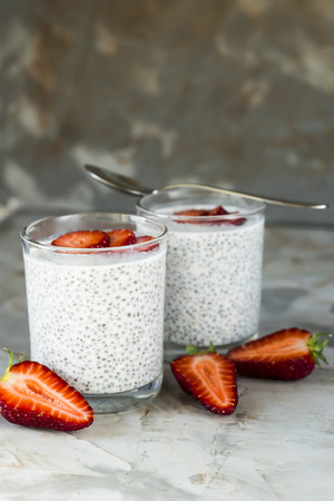Two servings of dessert made of chia seeds, milk and strawberries on a gray table. Healthy Breakfast Conceptの写真素材