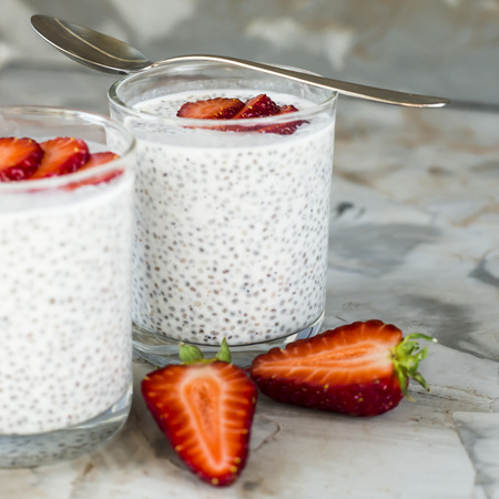 Two servings of dessert made of chia seeds, milk and strawberries on a gray table. Healthy Breakfast Conceptの写真素材