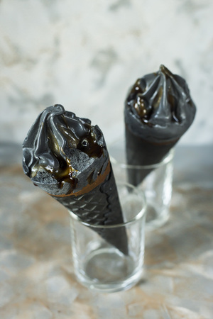 Two black ice cream in waffle cones on a gray background. Summer trend dessertの写真素材