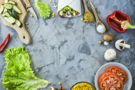 Cooking Mexican vegan burrito - vegetables and mushrooms and a prepared dish on a gray kitchen table. Top view, copyspaceの写真素材