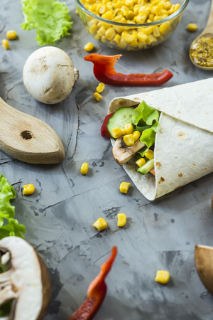 Vegan burrito from vegetables, mushrooms and tortillas. On a gray table among the ingredientsの写真素材