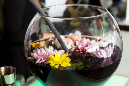 Red punch with buds of flowers in a glass round decanter on the bar counter. Summer party conceptの写真素材