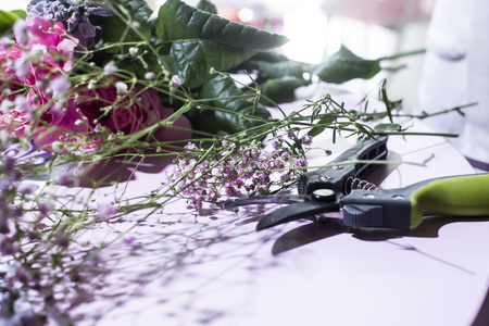 The workplace of the florist is a table with flowers and a prunerの写真素材
