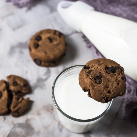 Chocolate biscuits next to a glass bottle and a glass of milk on a gray table. Top view, flat layの写真素材