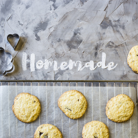 Word Homemade is written on a gray concrete background of flour. Next to the baking tray with cookies. Homemade pastry concept. Top view, flat layの写真素材