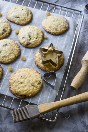 Homemade oatmeal cookies with chocolate chips on a gray kitchen table among accessories for bakingの写真素材