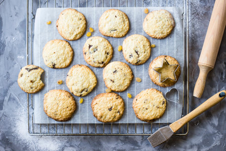 Homemade oatmeal cookies with chocolate chips on a gray kitchen table among accessories for baking....