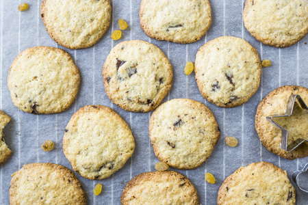 Homemade oatmeal cookies with chocolate chips on a gray kitchen table among accessories for baking. Top view, flat layの写真素材