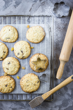 Homemade oatmeal cookies with chocolate chips on a gray kitchen table among accessories for baking. Top view, flat layの写真素材