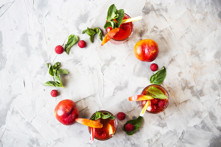 Light summer refreshing drink with fruits and berries - sangria with mint leaves and raspberry berries are filed in a circle. Top view, flat lay. Copyspaceの写真素材