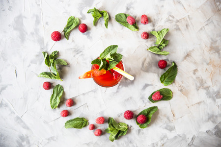 A light summer refreshing drink with fruits and berries - sangria next to mint leaves and raspberry berries on a gray background. Top view, flat layの写真素材