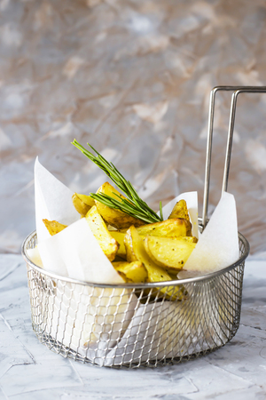 Sliced baked potatoes with spices and rosemary in a grid for deep frying. Fresh vegetable dish appetizerの写真素材