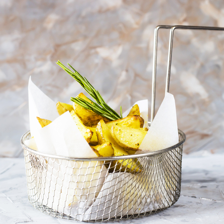 Sliced baked potatoes with spices and rosemary in a grid for deep frying. Fresh vegetable dish appetizerの写真素材