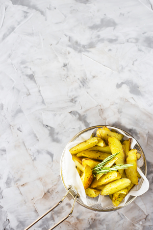 Sliced baked potatoes with spices and rosemary in a grid for deep frying. Fresh vegetable dish appetizer. Top view, flat lay, copy spaceの写真素材