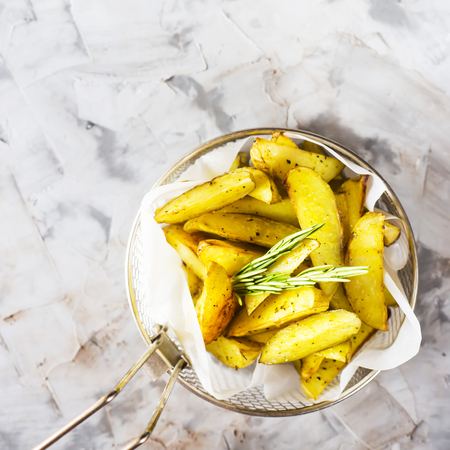 Sliced baked potatoes with spices and rosemary in a grid for deep frying. Fresh vegetable dish appetizer. Top view, flat lay, copy spaceの写真素材