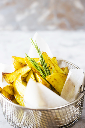 Sliced baked potatoes with spices and rosemary in a grid for deep frying. Fresh vegetable dish appetizerの写真素材