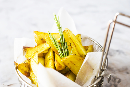 Sliced baked potatoes with spices and rosemary in a grid for deep frying. Fresh vegetable dish appetizerの写真素材