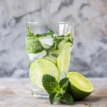 A glass of mojito with ice, mint and lime in a glass on a gray table. Summer soft drink conceptの写真素材