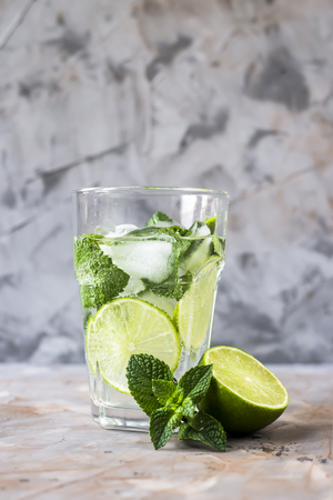 A glass of mojito with ice, mint and lime in a glass on a gray table. Summer soft drink conceptの写真素材