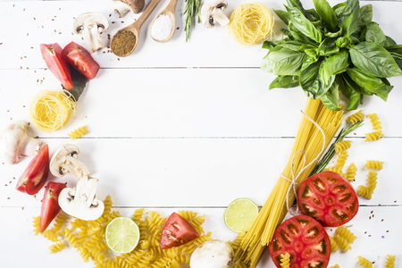 Food for cooking - pasta, basil, vegetables, lime and spices on a white wooden table in the shape of a circle. Top view, flat lay, copyspaceの写真素材