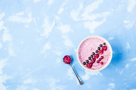 Berry smoothies with currants and raspberries on a bright blue background. Summer healthy snack. Copy space. Top viewの写真素材