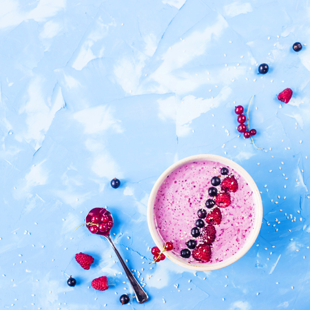 Berry smoothies with currants and raspberries on a bright blue background. Summer healthy snack. Copy space. Top viewの写真素材