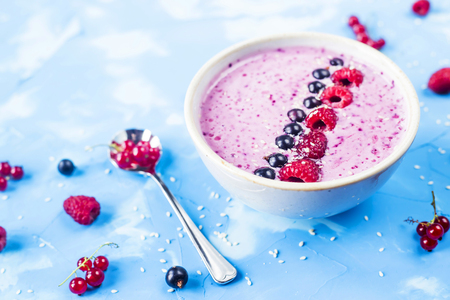 Berry smoothies with currants and raspberries on a bright blue background. Summer healthy snackの写真素材