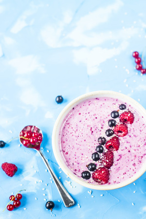 Berry smoothies with currants and raspberries on a bright blue background. Summer healthy snack. Copy space. Top viewの写真素材