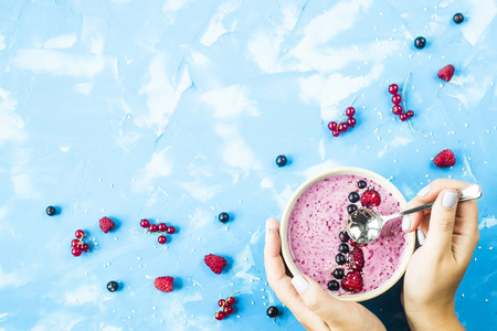 Berry smoothies with currants and raspberries on a bright blue background. Summer healthy snack. Copyspace. Top viewの写真素材