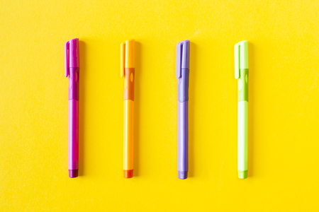 Multicolored four pen for writing on a yellow background . Top view, flat lay. Minimal chancery conceptの写真素材