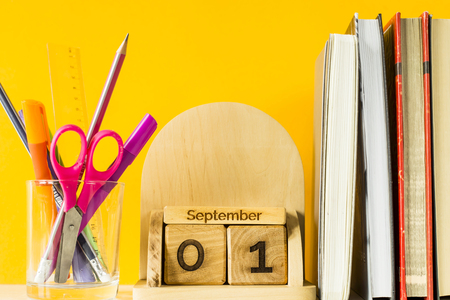 September 1 on a wooden calendar among textbooks and pens to study on a yellow background. Back to school conceptの写真素材